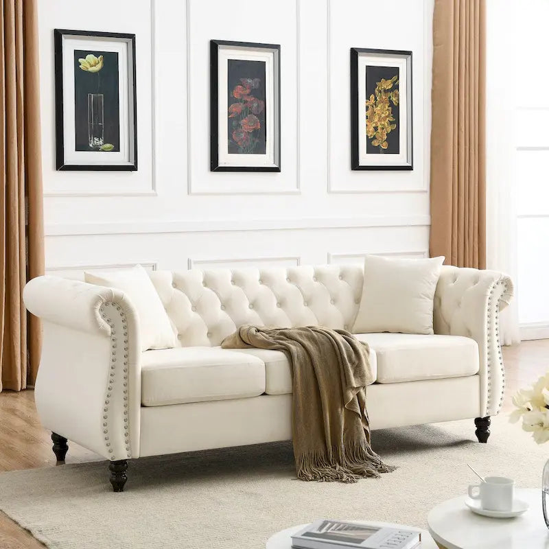 Canapé 3 places Chesterfield en velours beige, accoudoirs arrondis, garniture cloutée, structure en bois