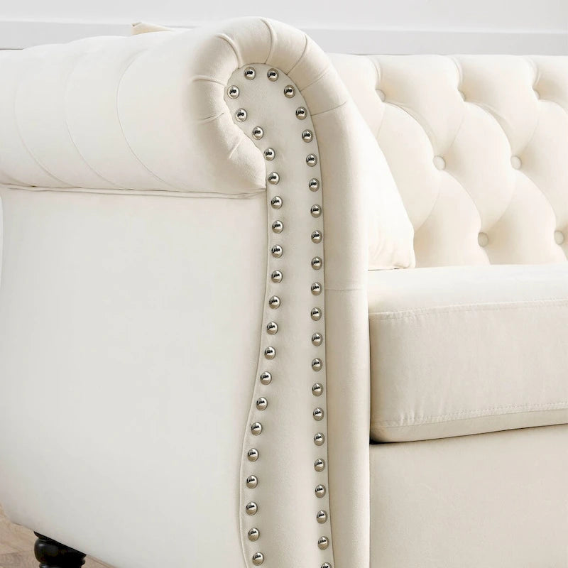 Canapé 3 places Chesterfield en velours beige, accoudoirs arrondis, garniture cloutée, structure en bois